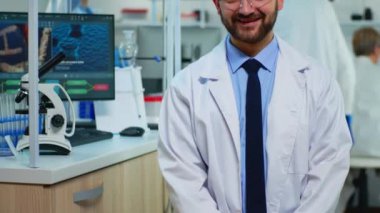 Modern laboratuvarda kameraya gülümseyen bilim adamının portresi.