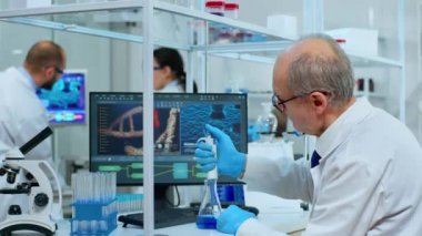Mikrokimyacı laboratuardaki test tüpüne mikro pipet kullanarak sıvı koyuyor.