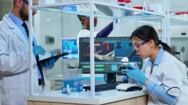 Bilim adamı ekibi mikroskop kullanarak sonuçları analiz ediyor