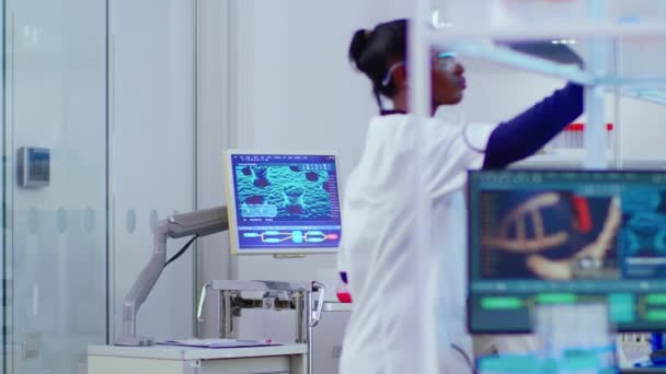 Zwarte jonge wetenschapper werkt in drukke moderne laboratorium — Stockvideo
