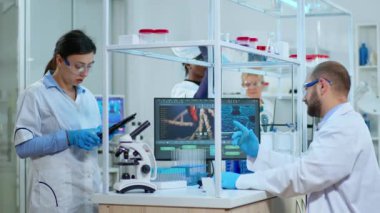 Bilim adamı hemşire laboratuardaki tablete not alıyor.