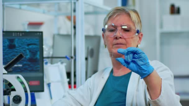 Técnico de laboratorio mujer mayor mirando la muestra de virus — Vídeo de stock