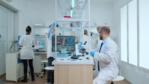 Homem cientista posicionamento placa de Petri sob microscópio em laboratório — Vídeo de Stock