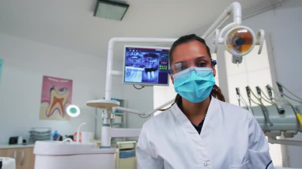Пациент в стоматологическом кресле периодически проверяет зубы — стоковое видео