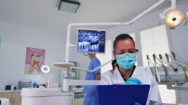 Diş hekimi hastayı sorguluyor ve not alıyor.