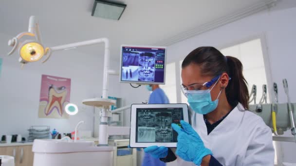 Пациент пов в стоматологическом кабинете обсуждает лечение зубов с помощью таблетки — стоковое видео