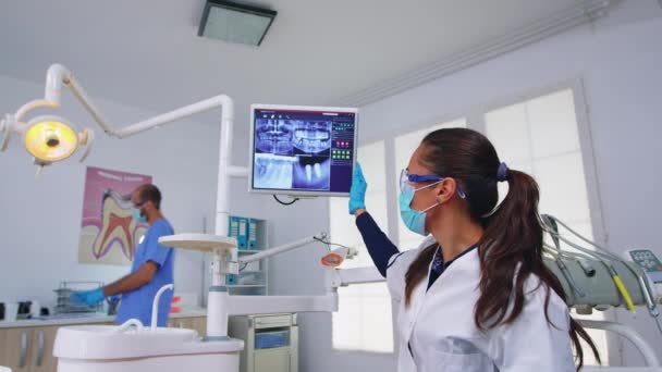 Лікар-стоматолог і пацієнт, дивлячись на цифровий рентгенівський промінь — стокове відео