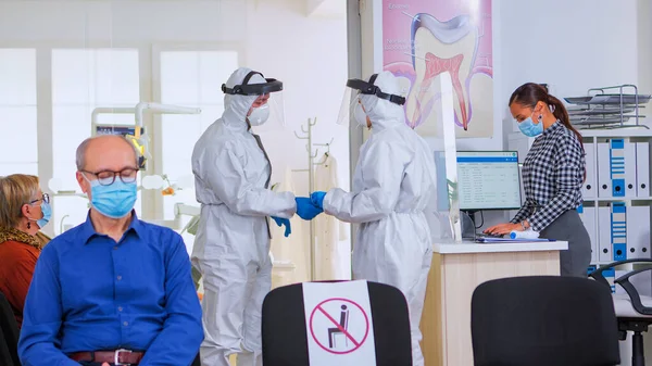 Врачи-стоматологи в защитном костюме проводят рентген зубов в приемной — стоковое фото