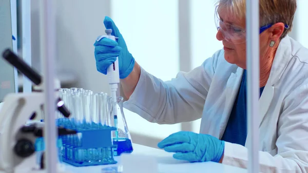 Científico en laboratorio médico examinando descubrimiento de drogas usando micropipeta — Foto de Stock