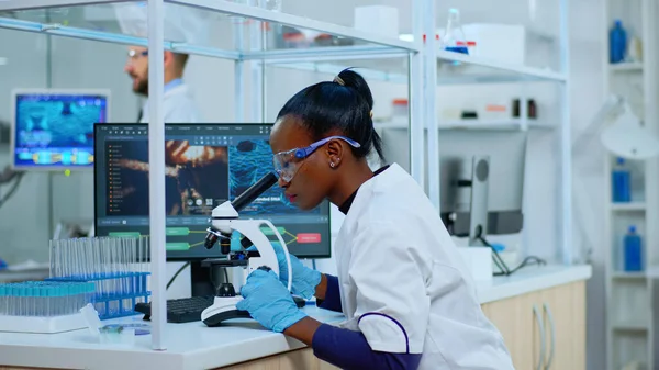 African scientist checking sample of virus using microscope — Stock Photo, Image