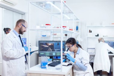 Erkek bilim adamı virüs çalışması sırasında tablet bilgisayarı üzerine notlar alıyor