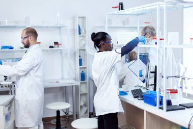 Profesyonel laboratuardaki Afrikalı kimyager çözeltili cam şişe alıyor.