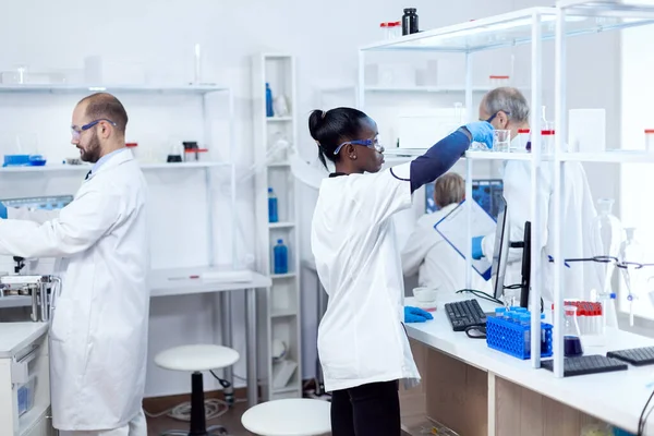 Químico africano en laboratorio profesional tomando un frasco de vidrio con solución —  Fotos de Stock