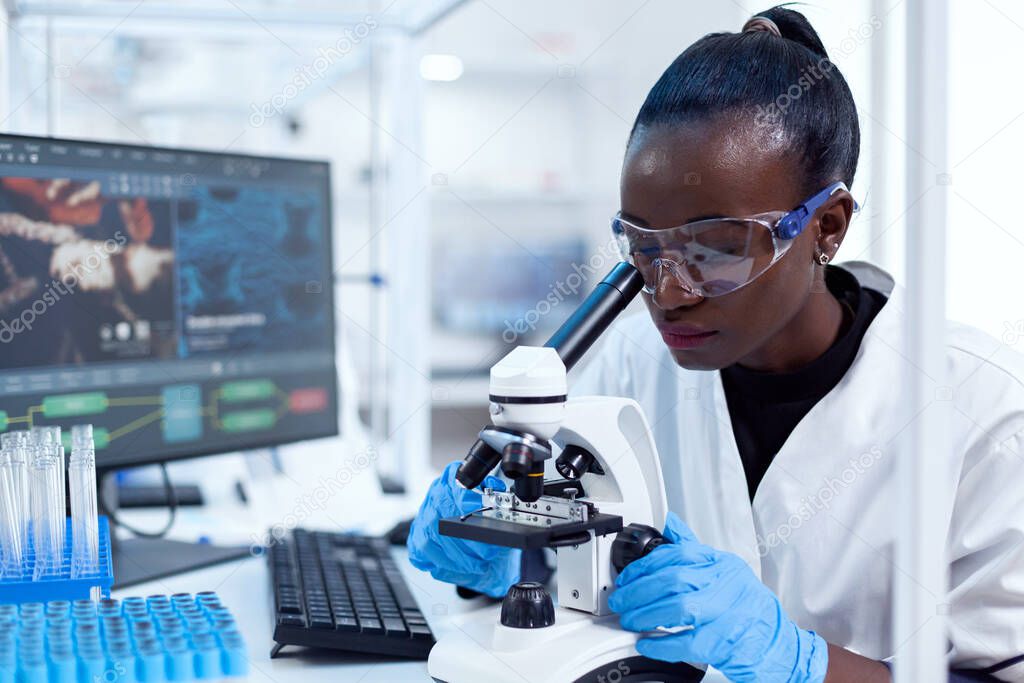 Medical researcher with african ethnicity using microscope