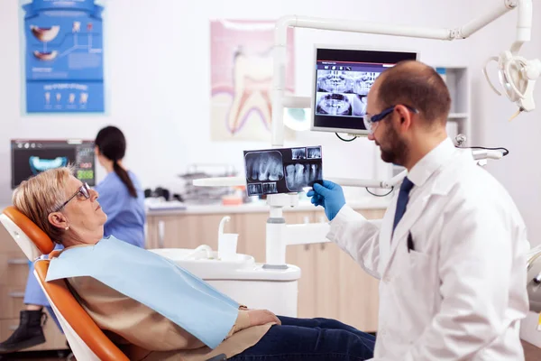 Tandarts kijken en onderzoeken bij senior vrouw tandheelkundige radiografie — Stockfoto