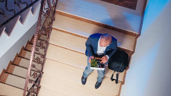 Top view of businessman getting fired sitting on staircase