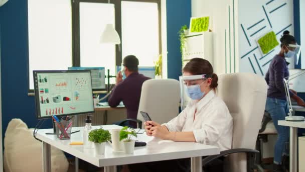 Bizneswoman z maską na czacie przy użyciu telefonu w biurze — Wideo stockowe