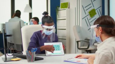 Çalışmayı tartışan ve dijital tablet kullanan çok ırklı iş kadınları