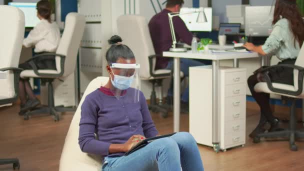 Zwart zakenvrouw met masker tegen covid19 werken op fauteuil — Stockvideo