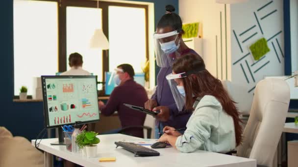 Багатоетнічні співробітники з масками захисту перевіряють щорічну статистику — стокове відео