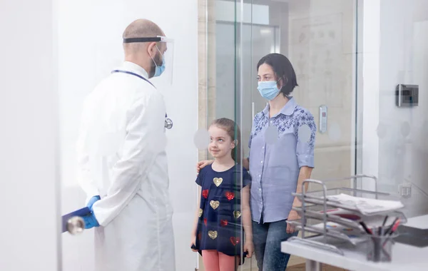 Педиатр в маске говорит с пациентом — стоковое фото