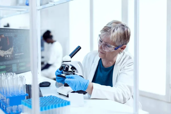 Científico senior poniendo diapositiva de vidrio en el microscopio durante la investigación médica —  Fotos de Stock