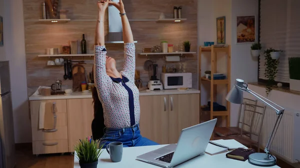 Remote employee streching while working on laptop