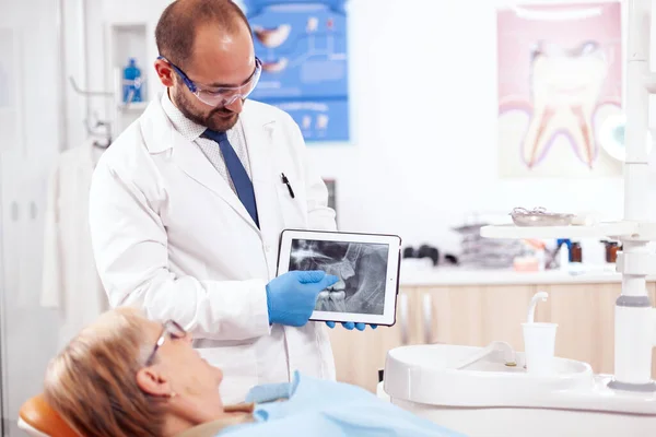 Стоматолог в стоматологическом кабинете, объясняющий диагноз зуба — стоковое фото