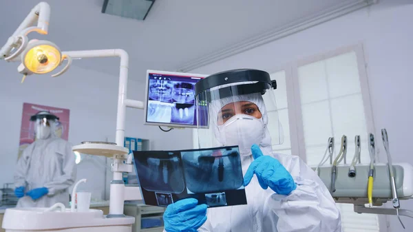 Пациент пов смотрит на стоматолога в костюме ppe с рентгеном зубов — стоковое фото
