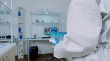 Korunma giysisindeki kimyager steril laboratuvara test tüpleri getiriyor.