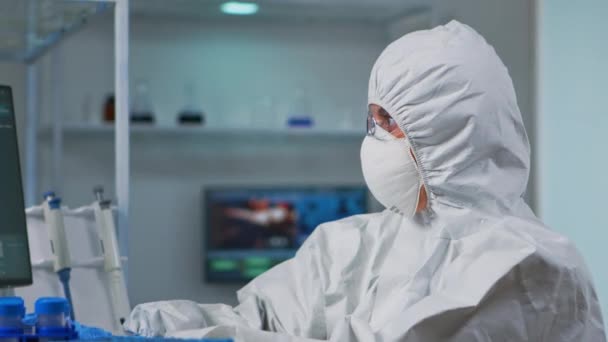 Крупним планом вчений в захисному костюмі друку на ПК — стокове відео