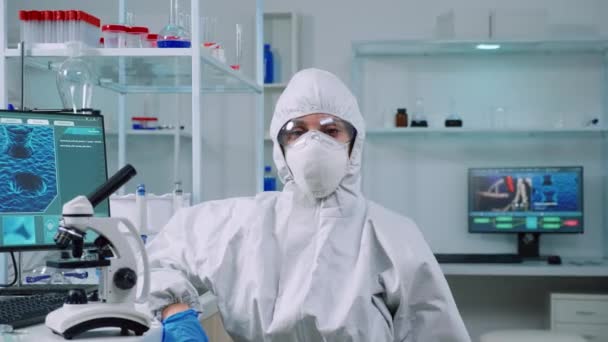 Microbiologista cansado em macacão sentado em laboratório olhando para a câmera — Vídeo de Stock