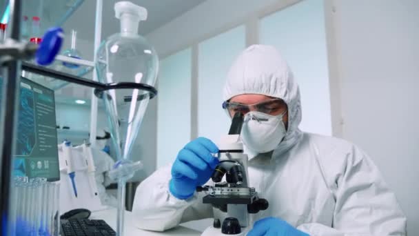 Onderzoeker in ppe pak die DNA-experimenten uitvoert — Stockvideo