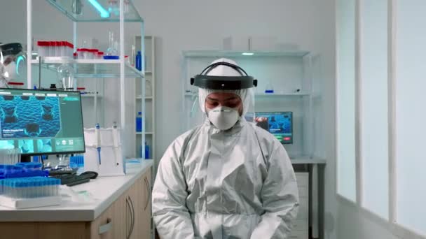 Cientista em terno ppe olhando exausto para a câmera no laboratório — Vídeo de Stock