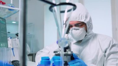 Kıyafet giymiş biyoteknoloji bilimcisi DNA araştırması yapıyor.