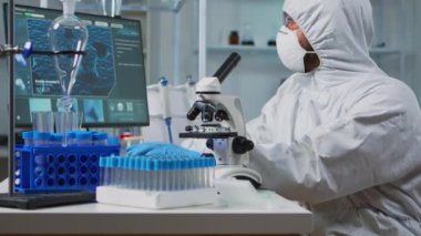 Takım elbiseli bir bilim adamının mikroskoptan baktığı yakın plan.