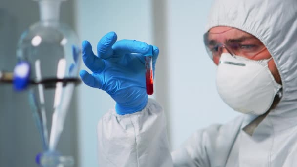 Científico sosteniendo muestra de sangre usando traje de protección — Vídeos de Stock