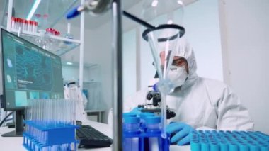 Araştırmacı bilim adamı mikroskop altında örneklere bakıyor.