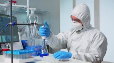 Modern laboratuarda deney tüpleriyle çalışan bir laboratuar bilimcisi.