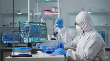 Mikro pipet kullanan kapaklı bilim adamı.