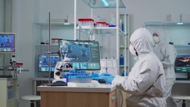 Chimiste en ppe costume dactylographier sur ordinateur vérifier le développement du virus — Video