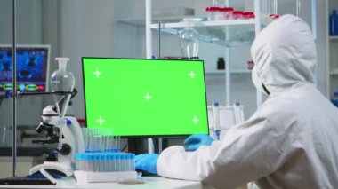Yeşil ekranlı bilgisayarda çalışan örtülü bir doktor.