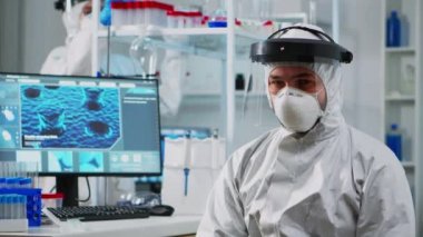 Koruyucu giysili doktor kameraya bitkin bakıyor.