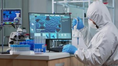 Kimyager pipet sıvısı test tüpü için koruyucu giysi giyiyor.