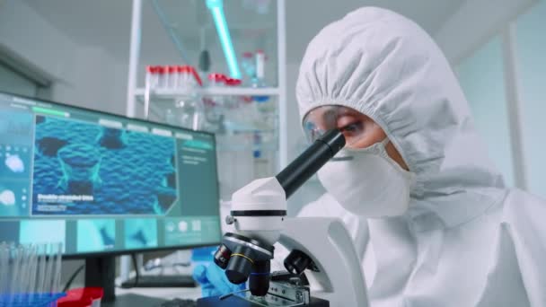 Enfermera en traje ppe haciendo experimentos médicos usando microscopio — Vídeos de Stock