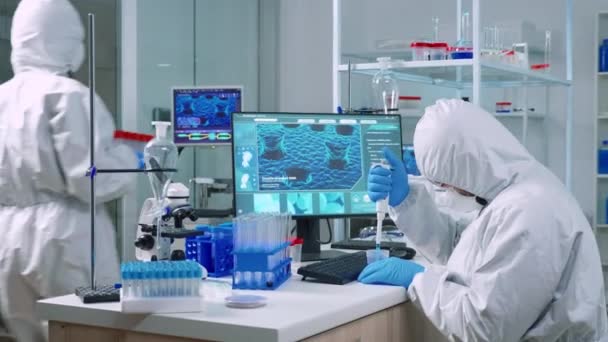 Scientifique portant une combinaison examinant la découverte de médicaments avec une micropipette — Video
