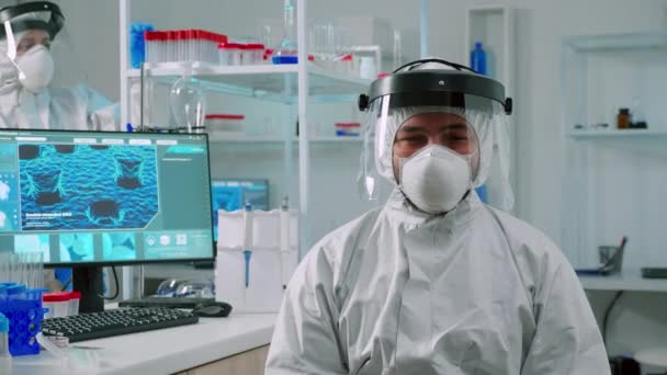 Overwerkte chemicus zittend in uitgerust lab draagt overall — Stockvideo