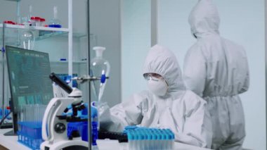 Laboratuvardaki bilim adamı mavi sıvıyla testler yapıyor.