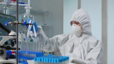 Pen giysili teknisyen deney tüplerini kontrol ediyor.