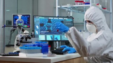 Pen giysili doktor test tüpündeki kan örneğine bakıyor.